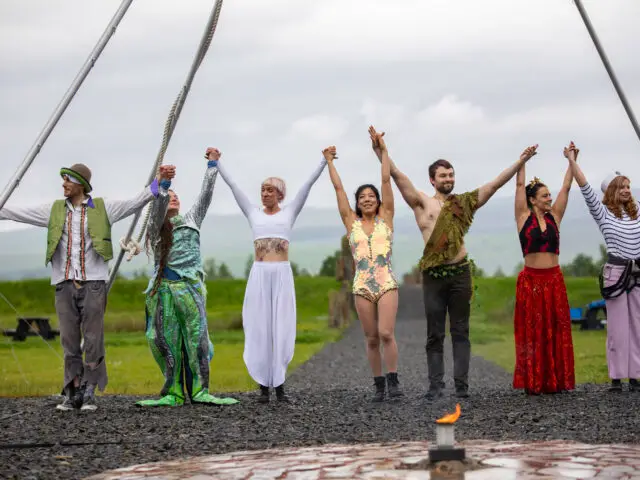 Performers standing outside in a row taking a bow.