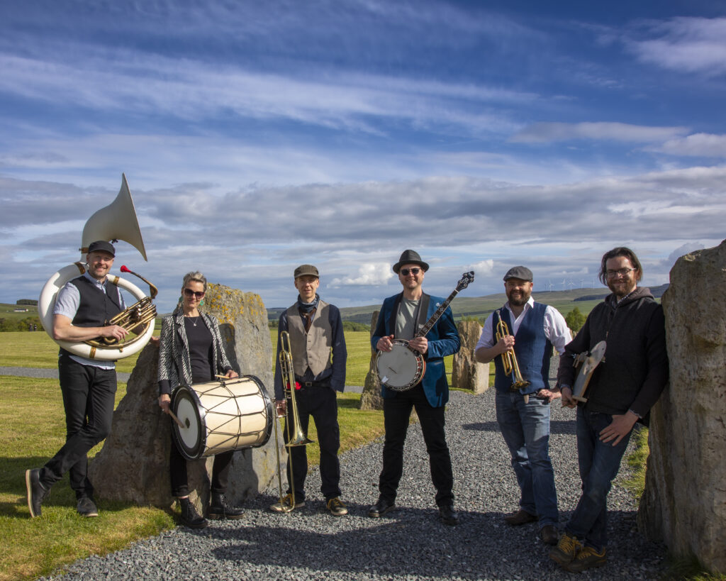 Members of a band standing together smiling holding their instruments.